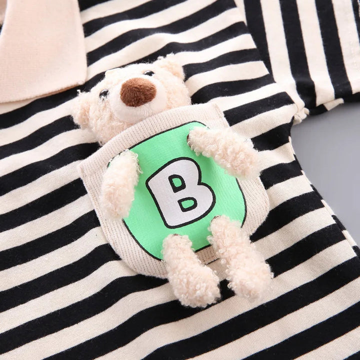 Close-up of the plush bear accent on the black-and-cream striped cotton T-shirt