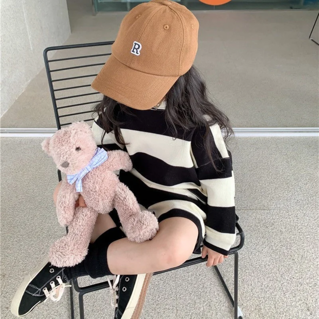 Seated child wearing the black-and-cream striped top and shorts set