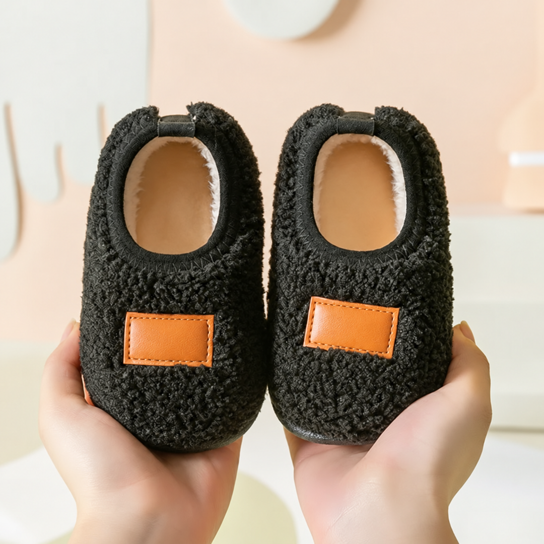 Black textured winter slippers with tan patches and pale opening trim
