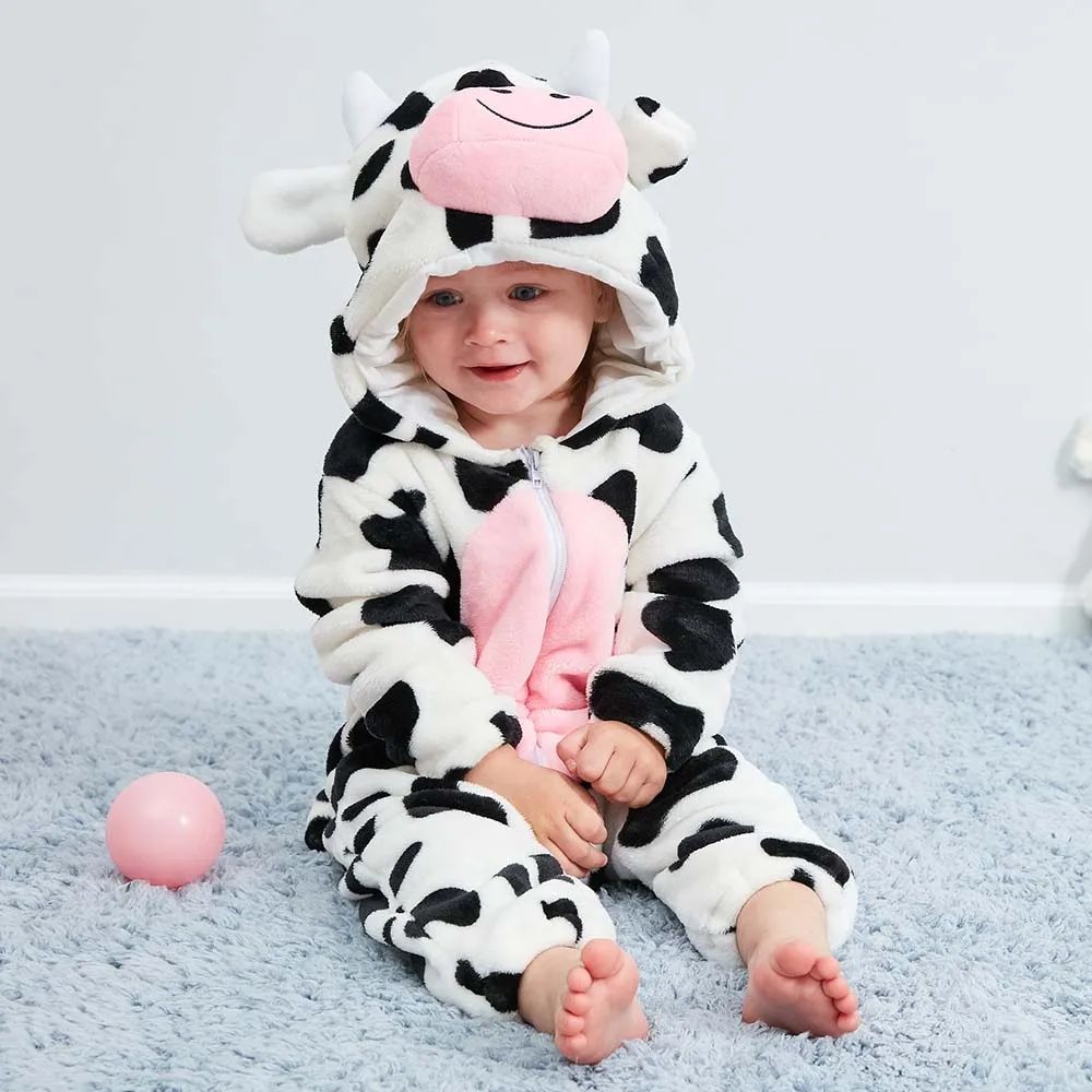 Baby sitting in a black-and-white cow onesie with a pink belly and cow-face hood