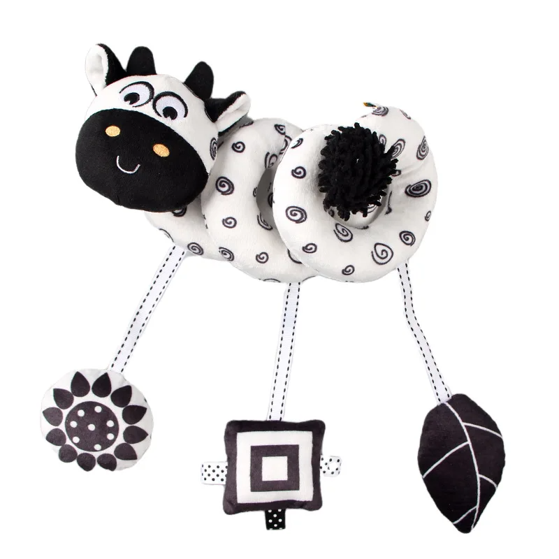 Black-and-white cow spiral activity toy with three hanging geometric and patterned shapes.