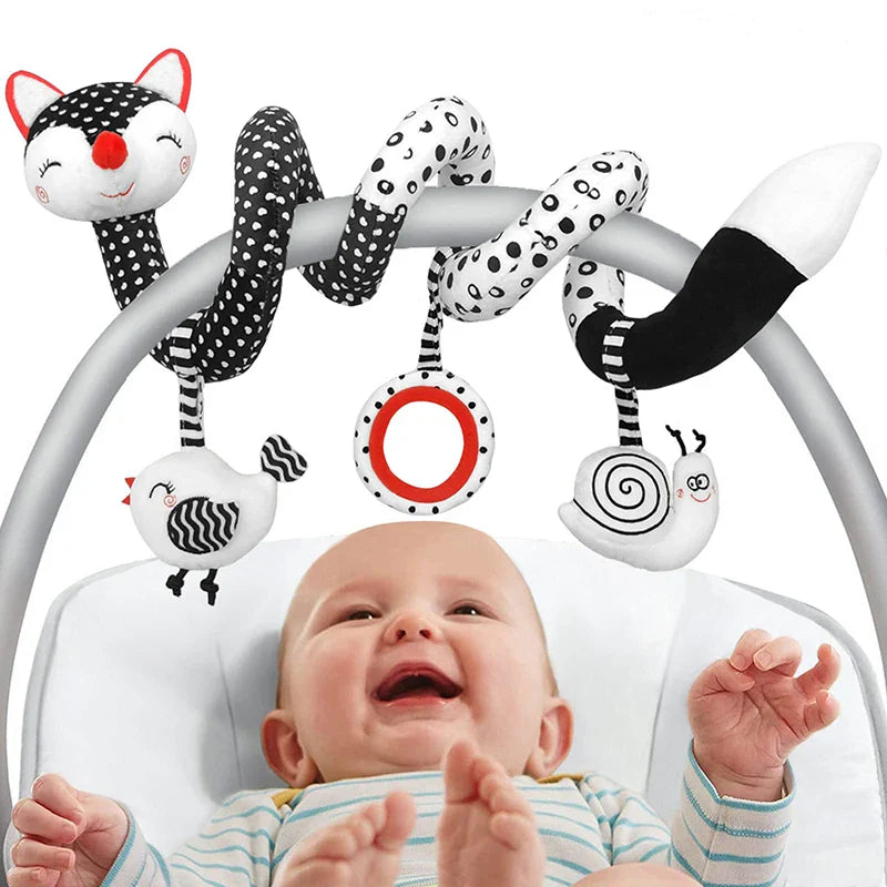 Baby beneath a black-and-white fox spiral activity toy wrapped around a seat handle.