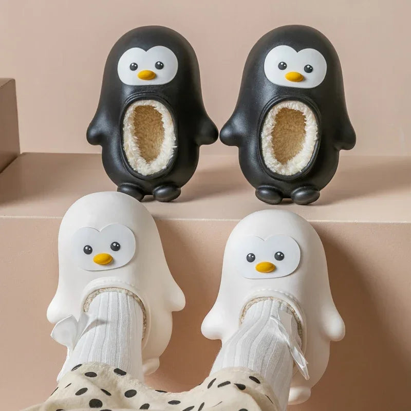 Black penguin slippers on a ledge above white penguin slippers worn with socks