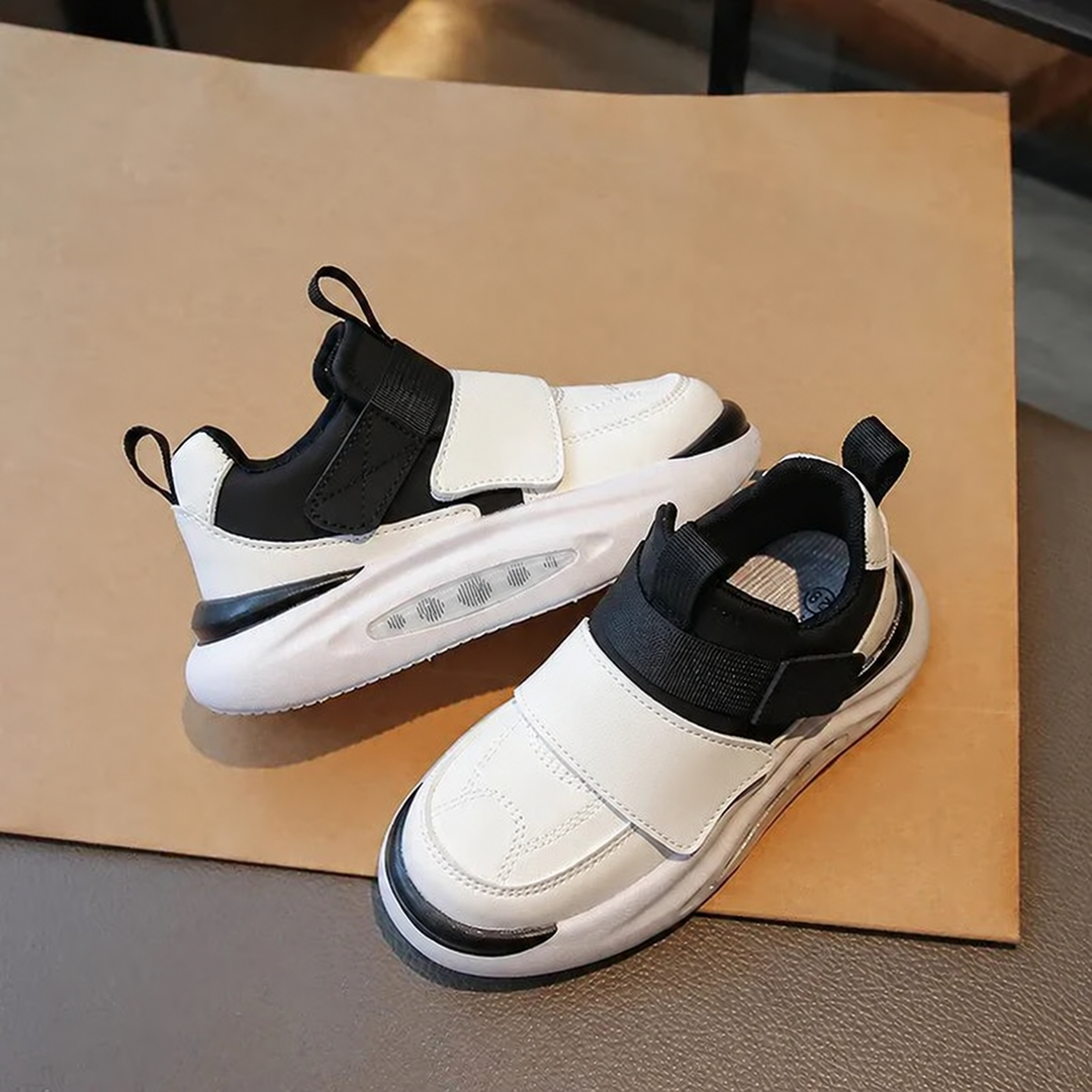 Black and white sneakers showing wide straps, pull tabs, and clear side panels in the soles
