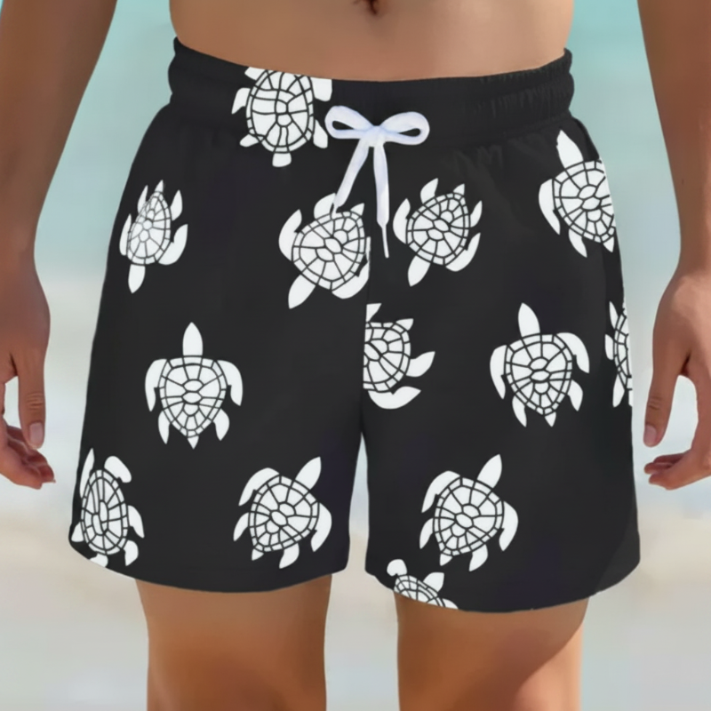 Black swim trunks with white turtle prints and a white drawstring, shown from the front