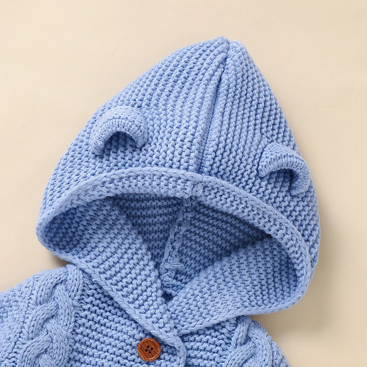Close-up of the blue knitted hood with small ears and a button at the neckline