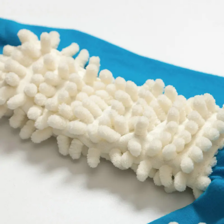 White cleaning fibers sewn onto the sleeve of a blue baby jumpsuit