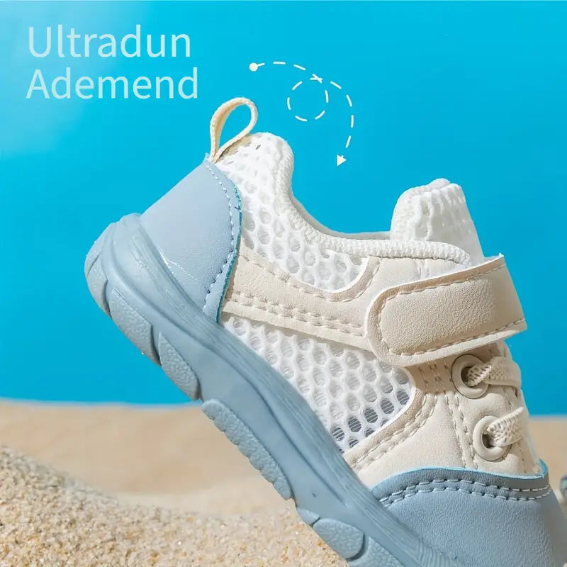 Side detail of a blue baby shoe showing open mesh panels, a white strap and a heel pull tab