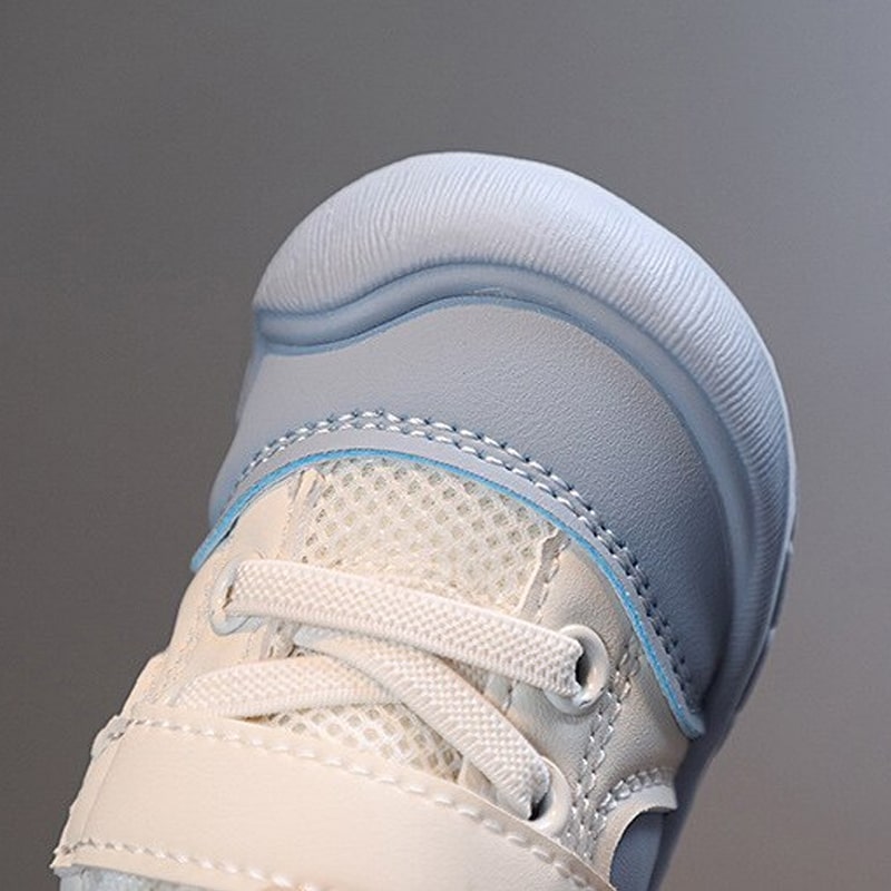 Close-up of the blue baby shoe's rounded toe, mesh tongue and white laces