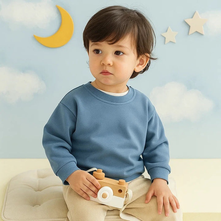 Child wearing a blue long-sleeve sweatshirt with ribbed cuffs and hem
