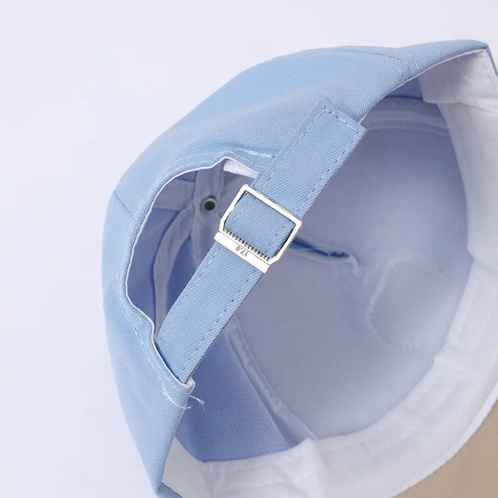 Close-up of the adjustable back strap and metal buckle on a light blue baseball cap