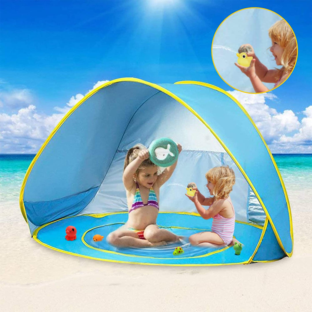 Two children playing with toys inside a blue pop-up tent on the beach