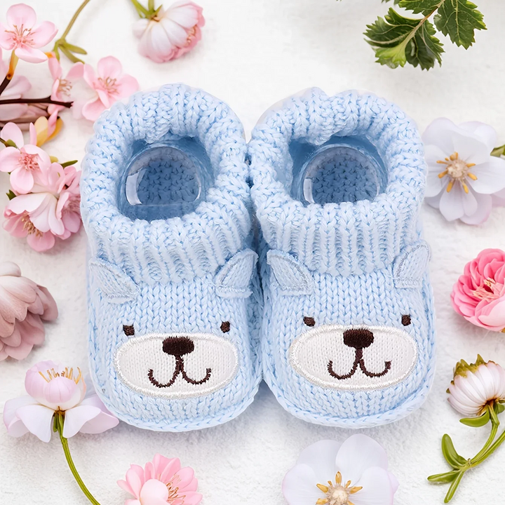 Light blue knitted baby booties with bear faces and folded ribbed cuffs