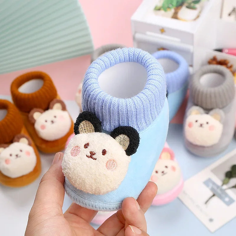 Blue bear slipper held in one hand, showing its plush face and ribbed collar