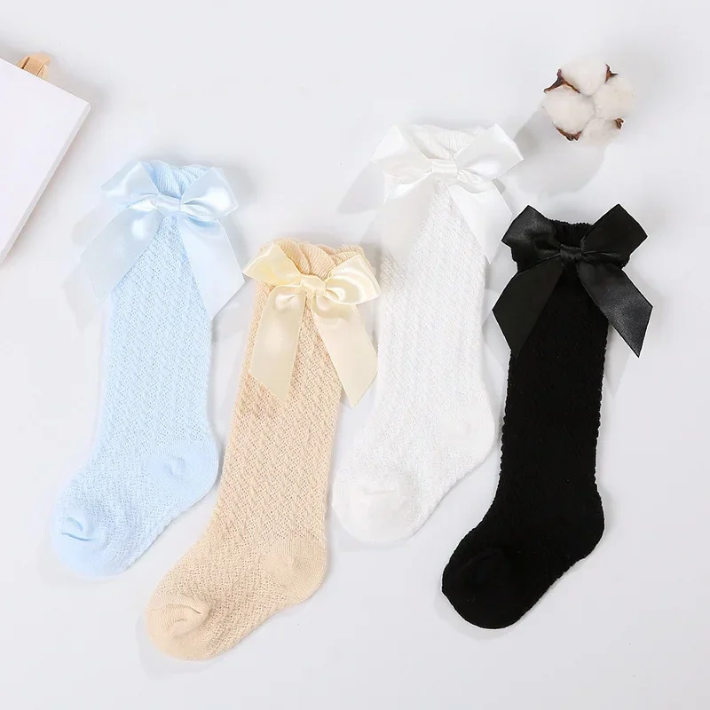 Blue, beige, white, and black pointelle knee-high socks with matching bows