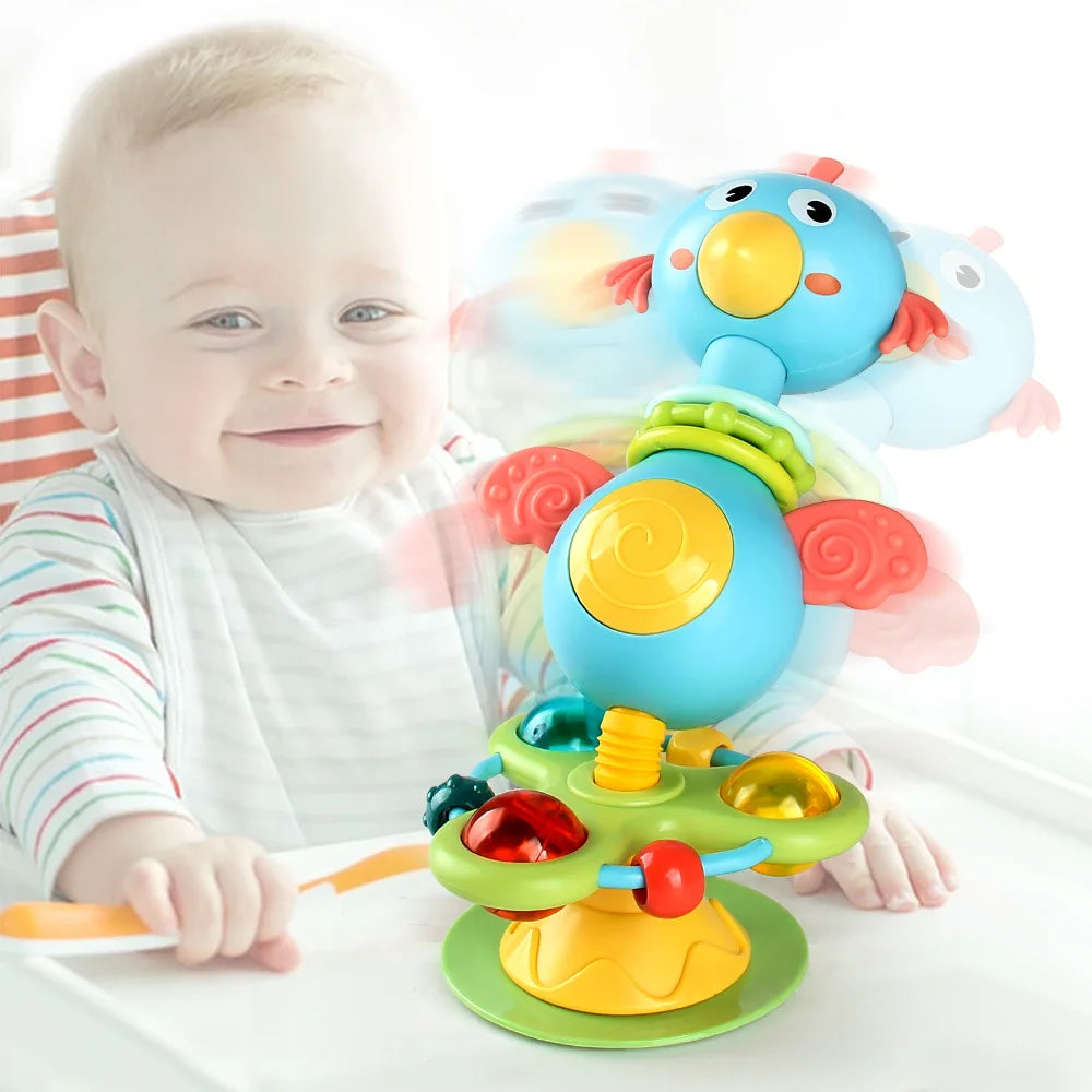 Baby beside a blue bird suction cup rattle on a high chair tray