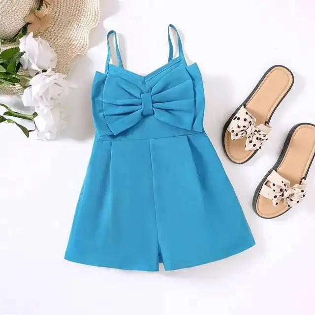 Blue bow-front romper laid flat with sandals, white flowers and a straw hat