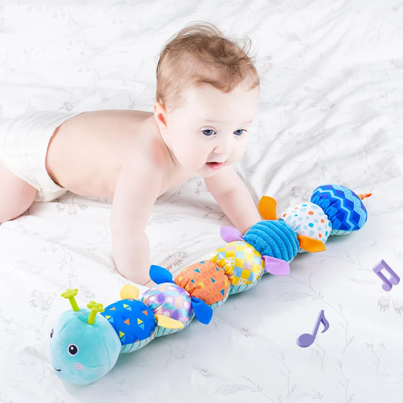 Blue caterpillar rattle in front of a baby during tummy time, with musical note graphics