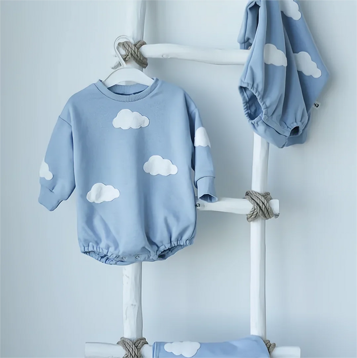 Blue long-sleeve cloud romper displayed on a white ladder rack.