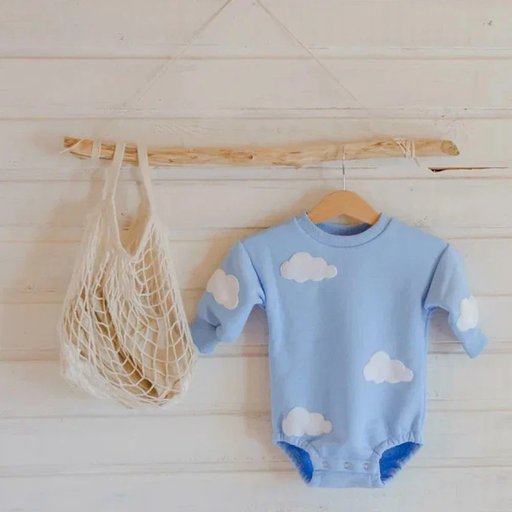 Blue cloud-detail baby romper on a wooden hanger, showing the gathered leg openings.