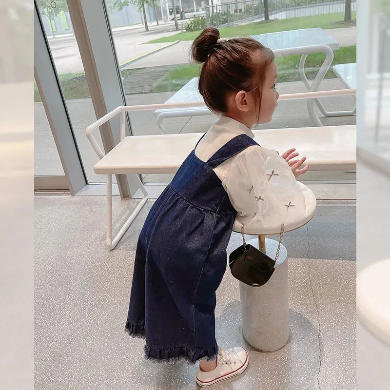 Side view of blue cotton overalls with wide legs and fringed hems