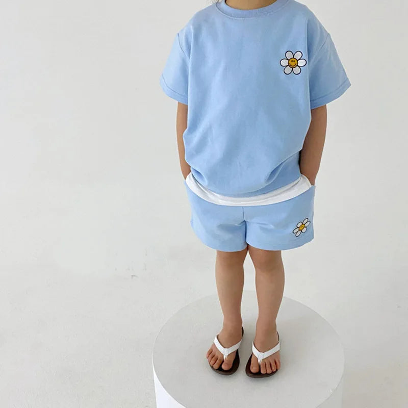 Child wearing a blue short-sleeve daisy T-shirt and matching shorts