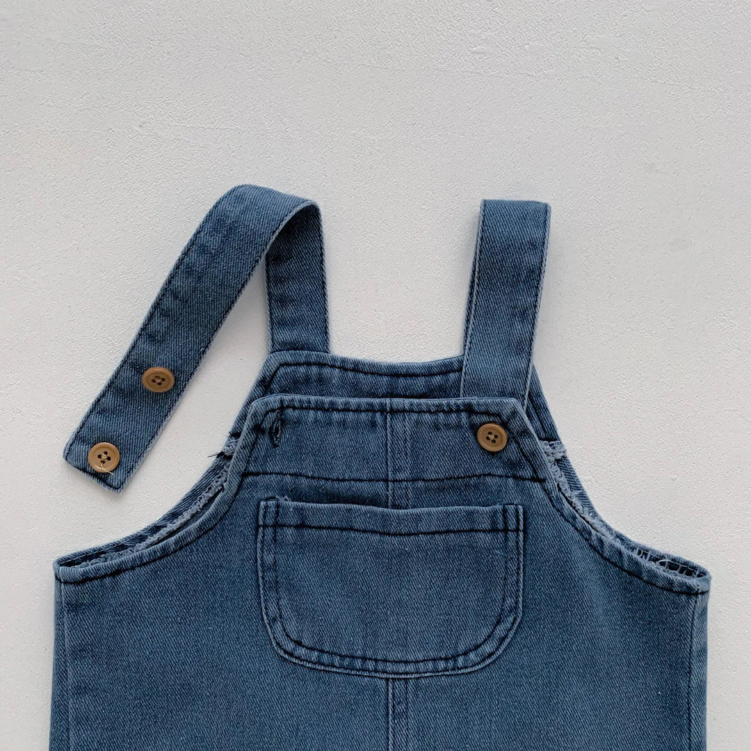 Blue denim bib overalls showing the front pocket and buttoned shoulder straps