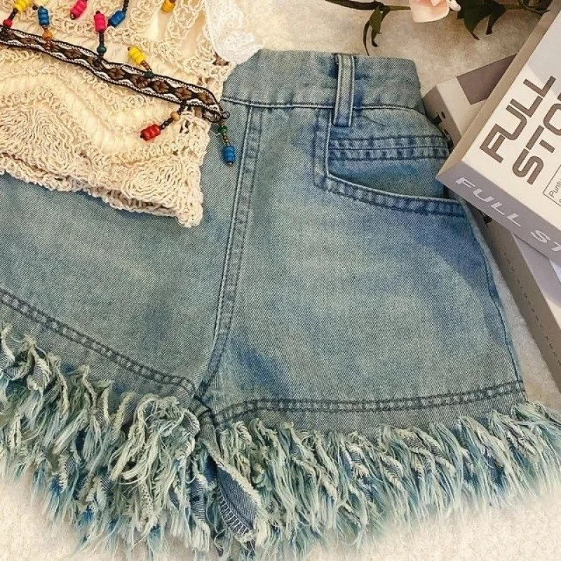 Blue denim shorts showing a back pocket, belt loops, and fringed leg openings