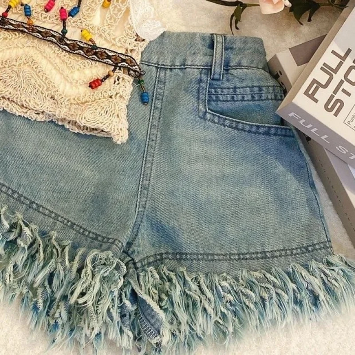 Blue denim shorts showing a back pocket, belt loops, and fringed leg openings