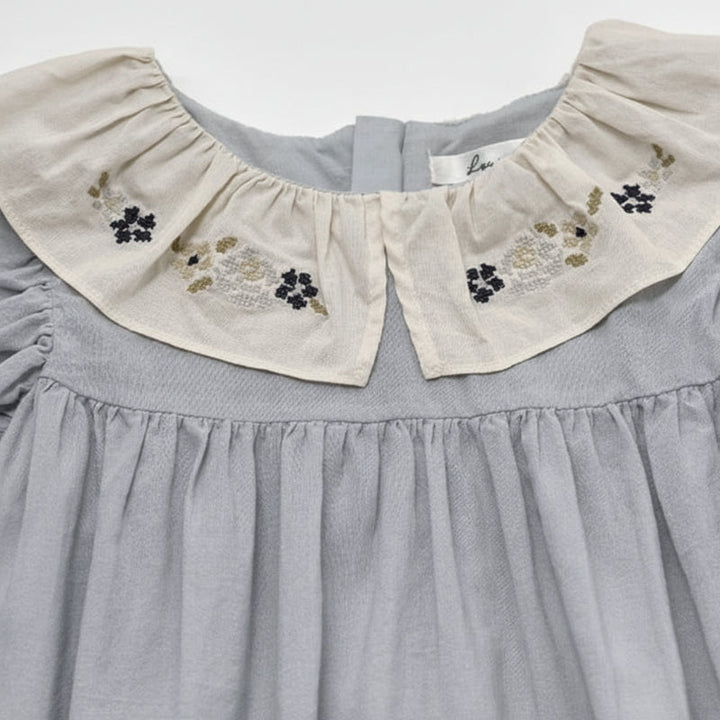 Close-up of floral embroidery on the blue dress&