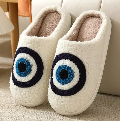 Cream plush slippers with blue, white and dark circular eye motifs.