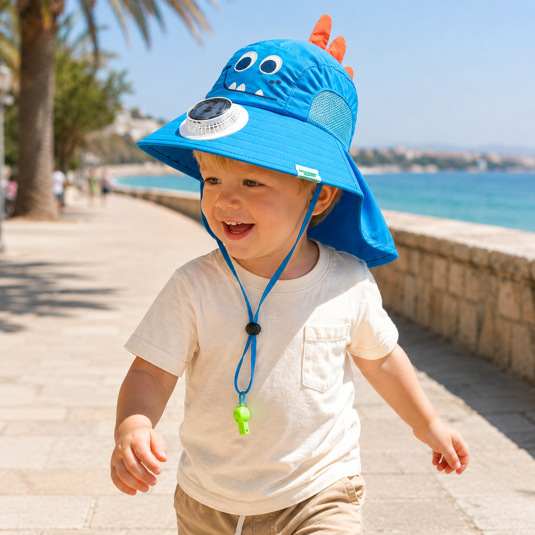 Child wearing a blue dinosaur fan hat with a neck flap on a seaside walkway.