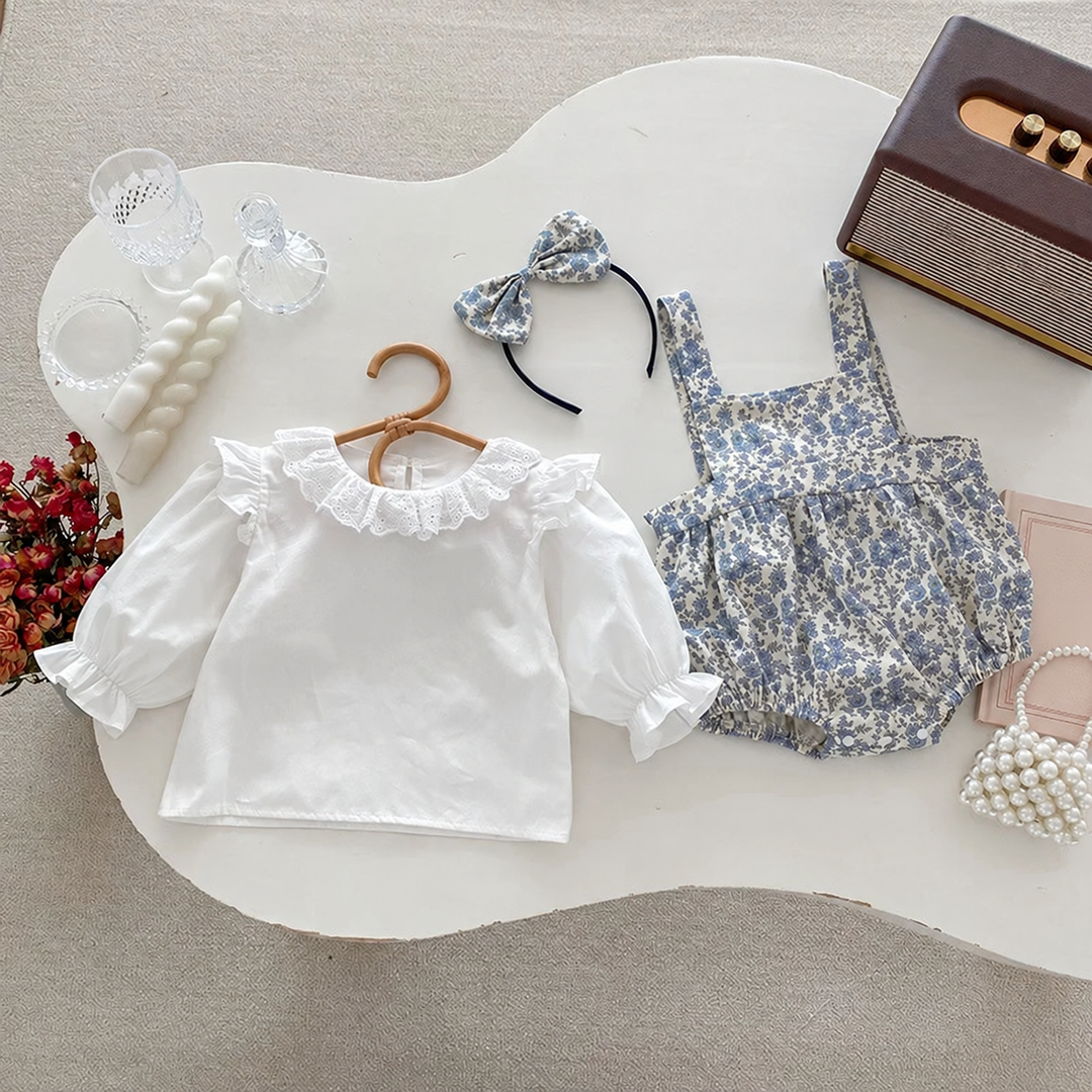 White puff-sleeve top, blue floral bodysuit, and matching bow headband laid out separately
