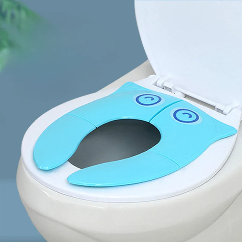 Blue folding toilet training seat resting on a white toilet seat