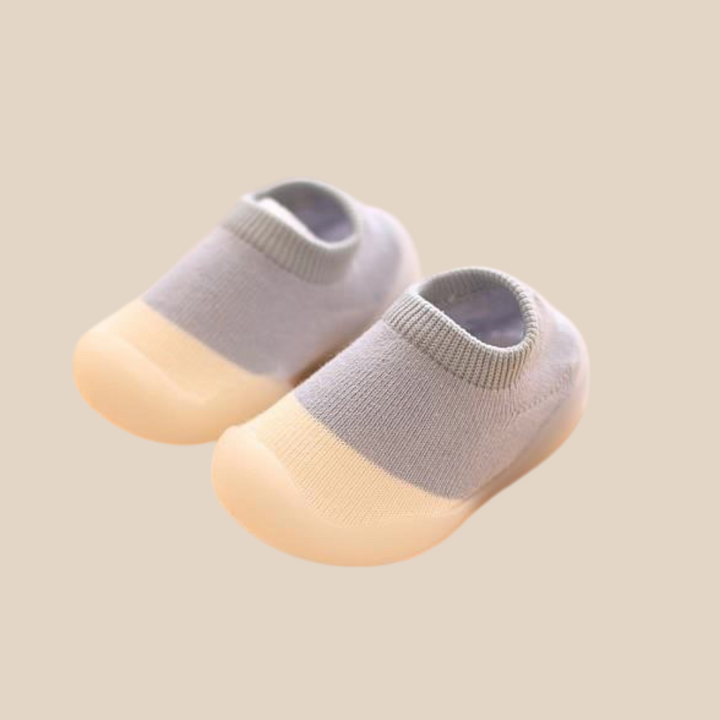 Pair of blue-gray knit baby shoes with cream toe sections and ribbed openings.