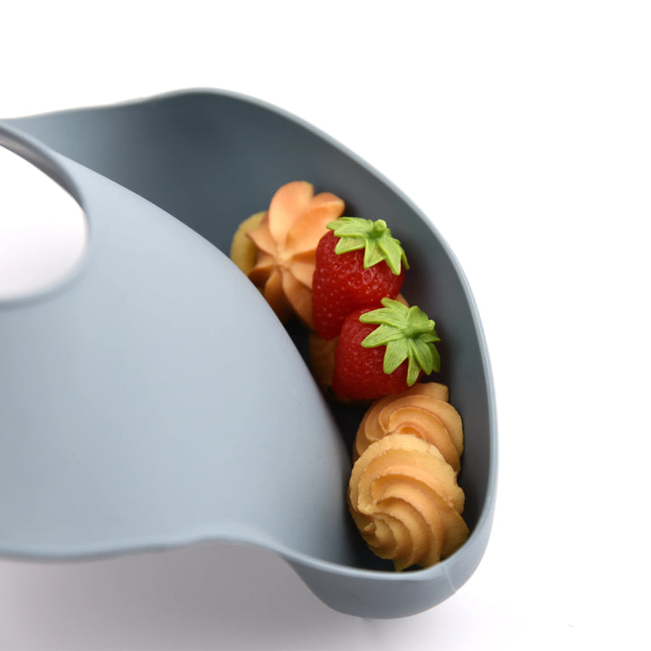 Blue-gray silicone bib pocket holding strawberries and small snacks.