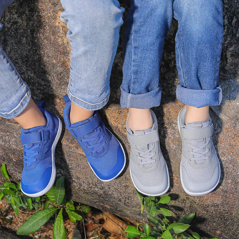 Blue and gray kids' sneakers worn side by side on a rock