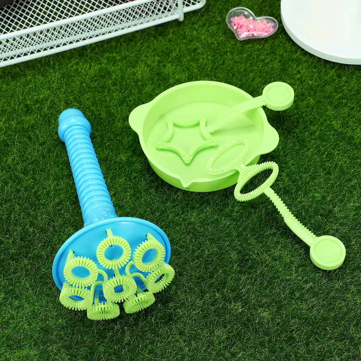 Blue multi-ring bubble blower beside a green dipping tray and wands on grass