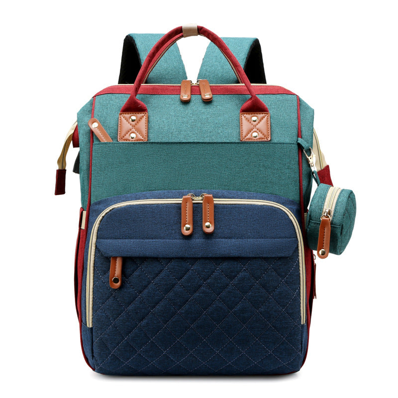Blue-and-green diaper backpack with red handles and a quilted front pocket