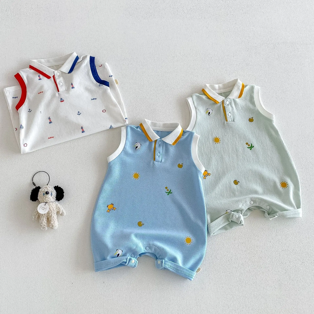Light blue and light green polo rompers laid flat beside a folded white nautical-print romper