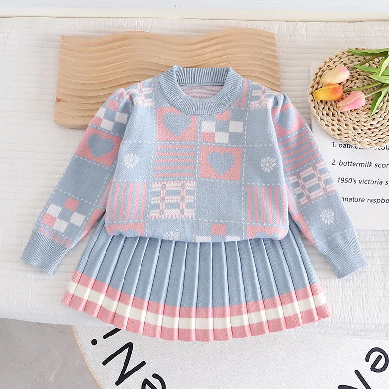 Blue knit sweater with pink heart and check patterns, paired with a pleated skirt with a pink-and-white striped hem