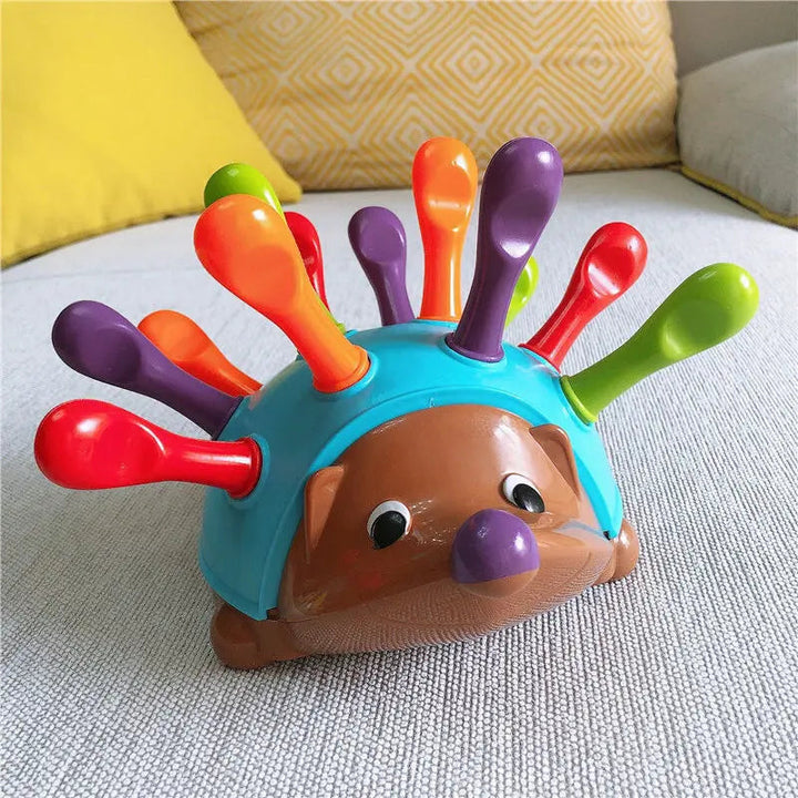 Hedgehog learning toy with red, green, orange, and purple quills on a sofa