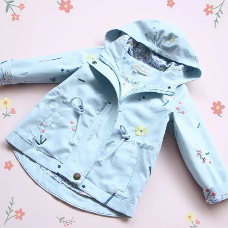 Blue hooded windbreaker laid flat, showing nature-inspired details, pockets, and a drawstring waist