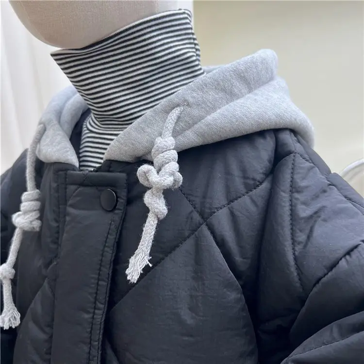 Close-up of a gray hood and navy blue quilted jacket over a striped turtleneck.