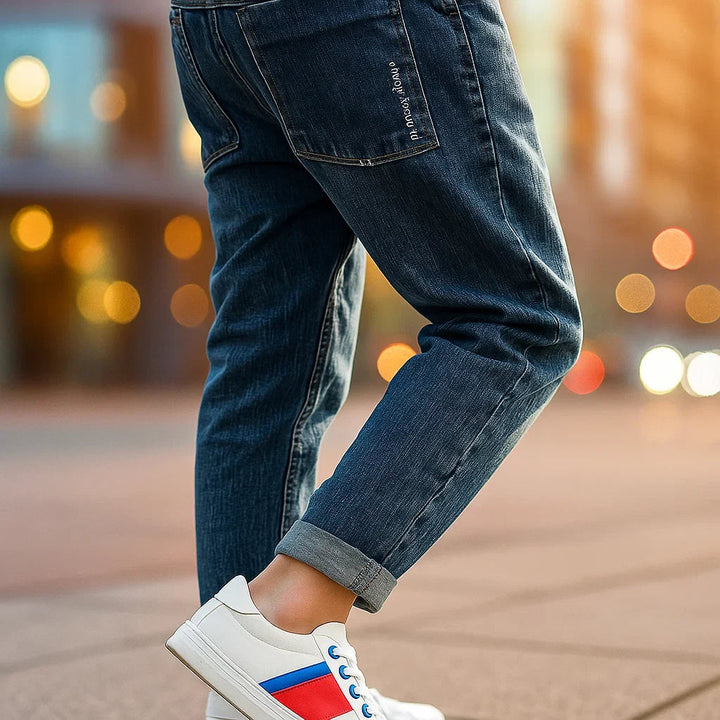 Rear view of blue jeans showing a stitched back pocket and rolled cuff.