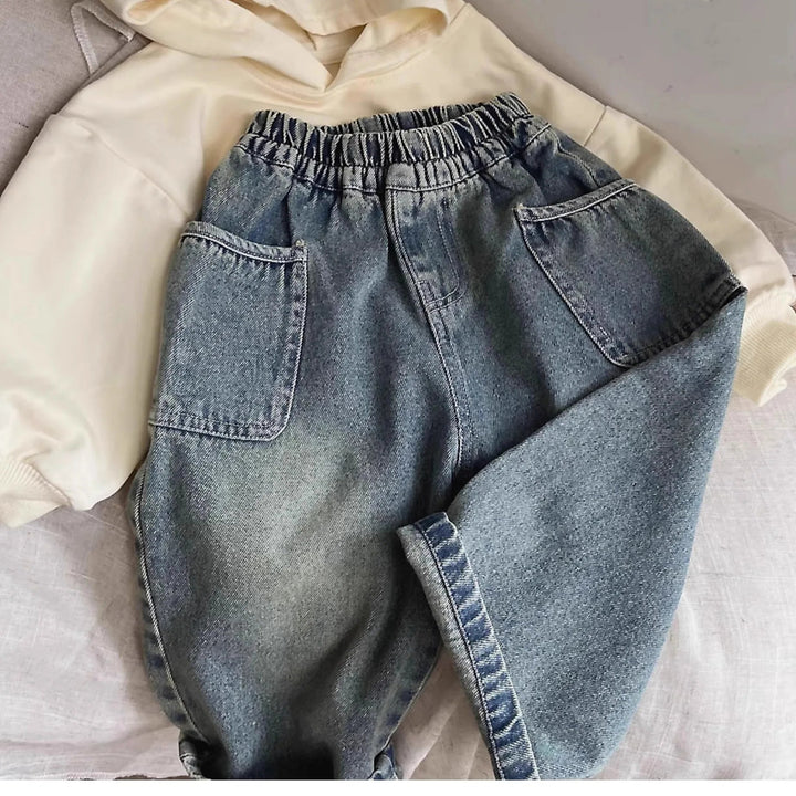 Plain blue jeans with an elastic waist and one leg folded across a cream top