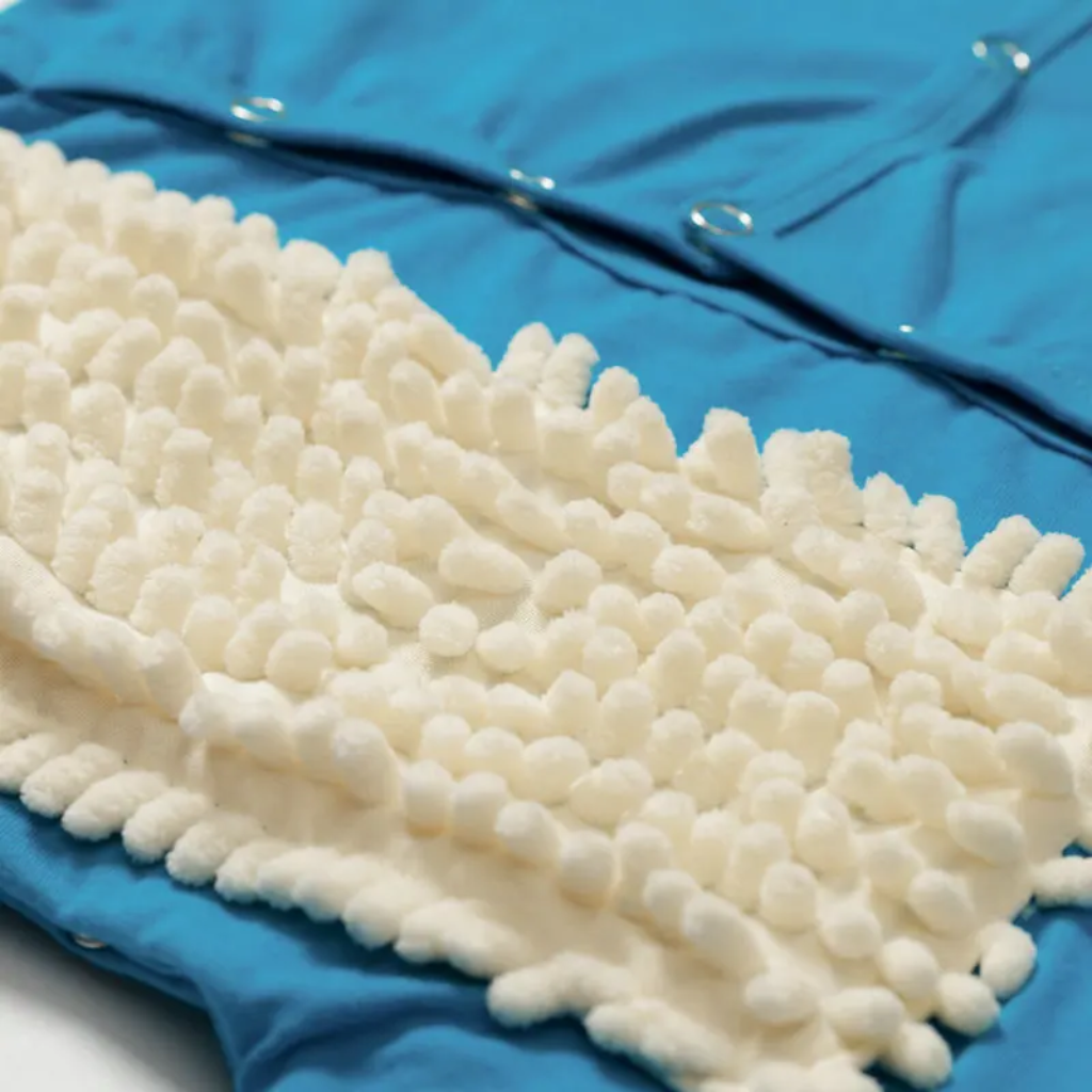 White cleaning fibers and back snaps on a blue baby jumpsuit