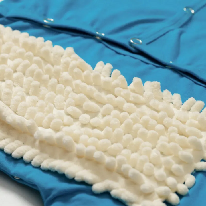 White cleaning fibers and back snaps on a blue baby jumpsuit