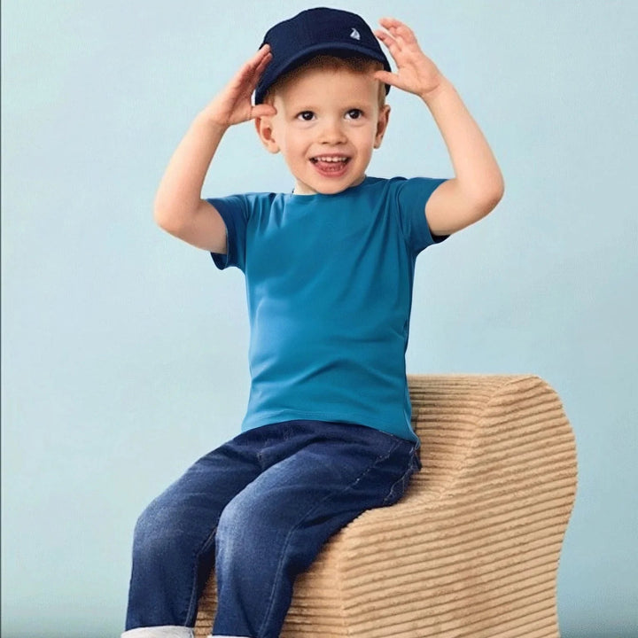 Boy in a blue T-shirt and jeans sitting on a woven seat