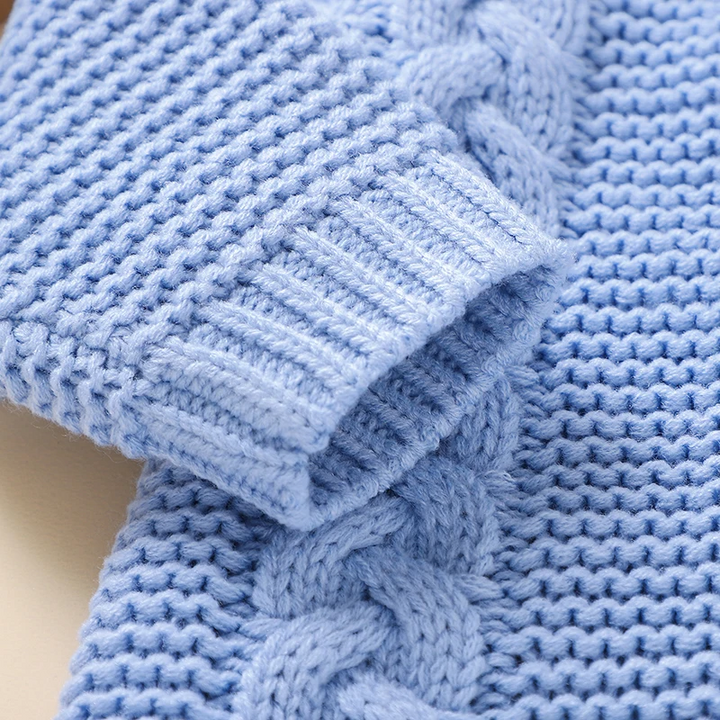 Blue knitted sleeve showing a ribbed cuff beside raised cable detailing